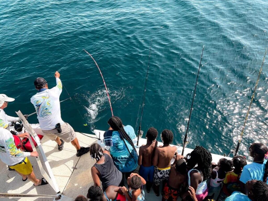 Florida Fishing Academy students watching a fish being reeled in on the boat.  